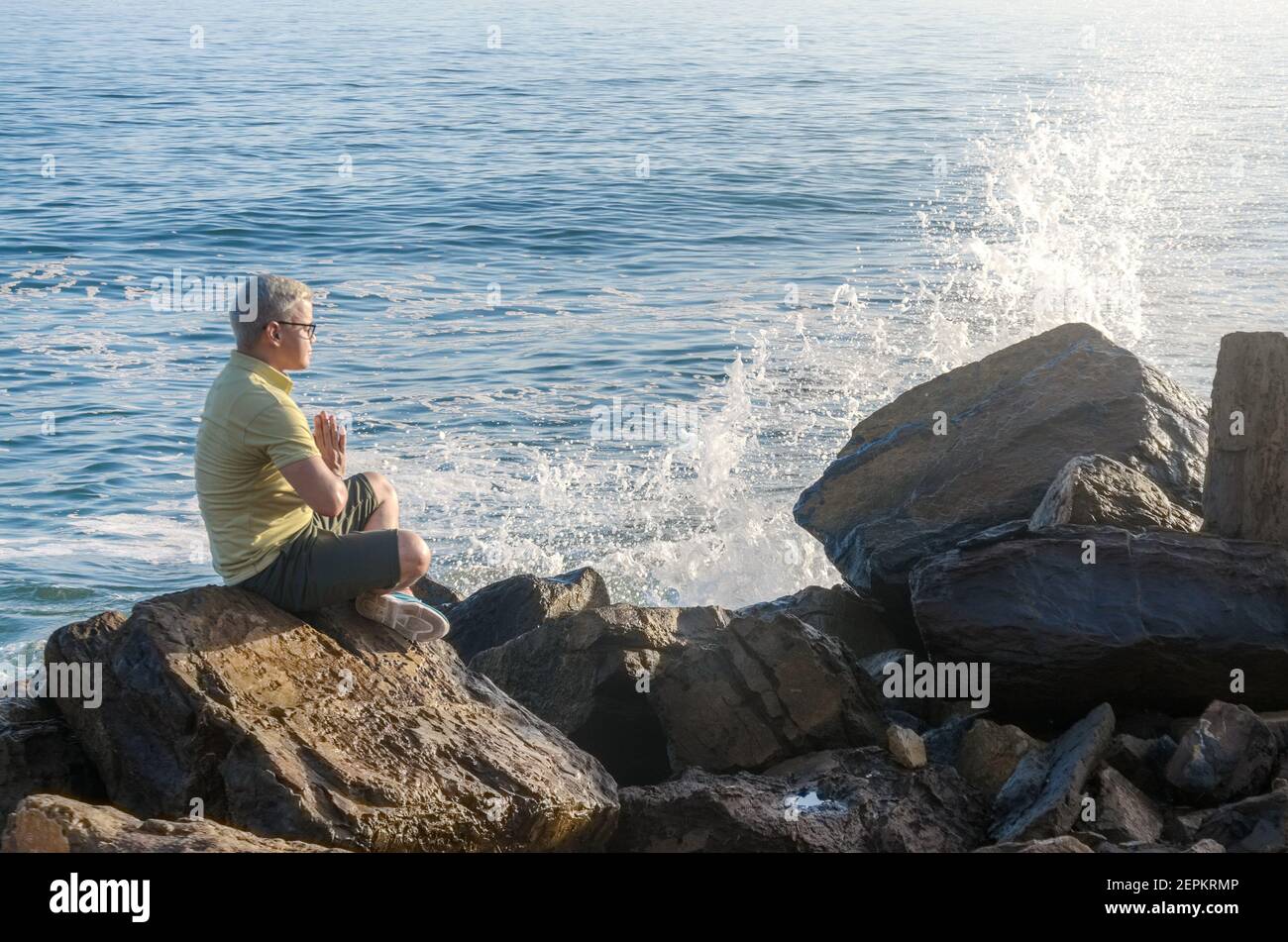 Uomo che medita sulla roccia nella costa della spiaggia Foto Stock