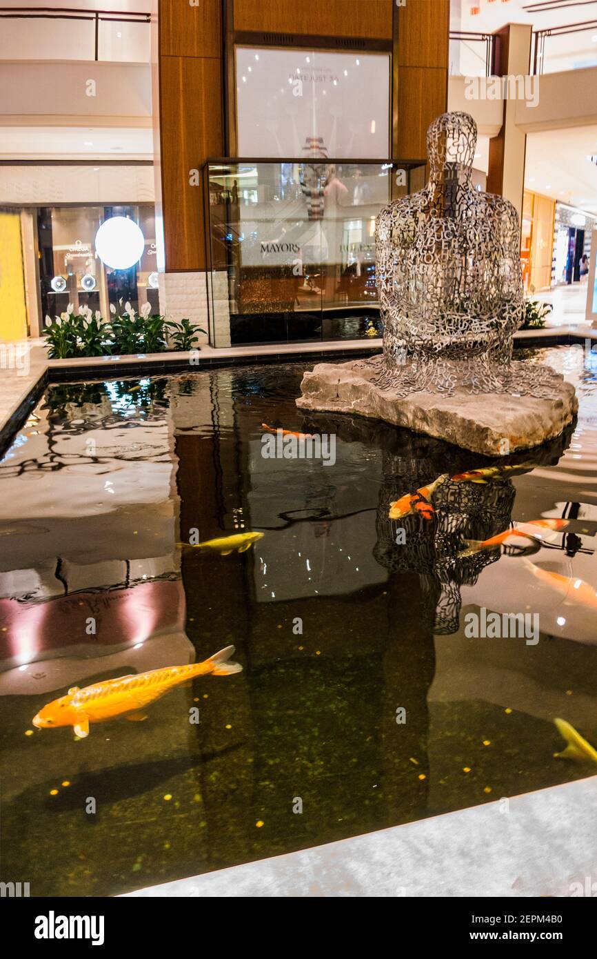 Coy nuotare in uno stagno evidenziato da una scultura astratta al centro commerciale Adventura vicino a Miami, Florida. Foto Stock