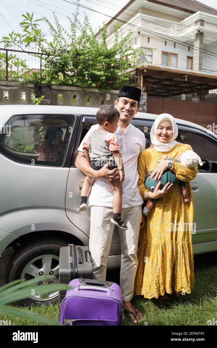 La famiglia musulmana viaggia in auto durante la celebrazione di eid mubarak. Persone asiatiche sorridenti mentre si levano in piedi davanti alla casa prima di partire per un viaggio in auto Foto Stock