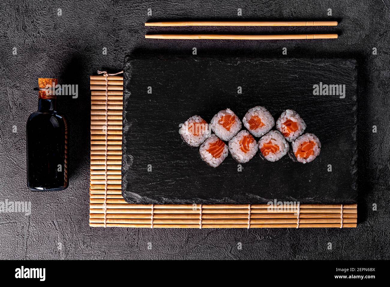 Classico sushi giapponese con salmone. Sfondo nero e decorazioni nere. Foto Stock