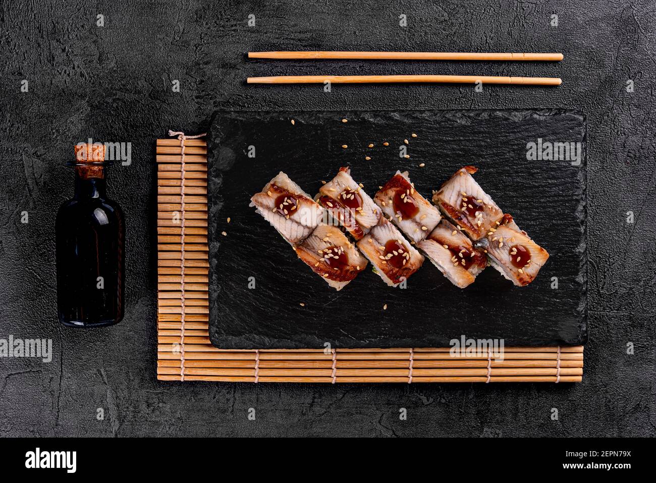 Sushi roll (Philadelphia) con salmone, anguilla affumicata, avocado, formaggio cremoso su sfondo nero. Menu sushi. Cibo giapponese. Foto Stock