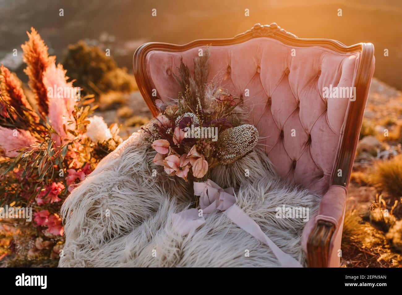 Poltrona rosa con fiori su morbido plaid posto su vintage tappeto con piume  decorative sulla collina in natura durante il matrimonio celebrazione Foto  stock - Alamy