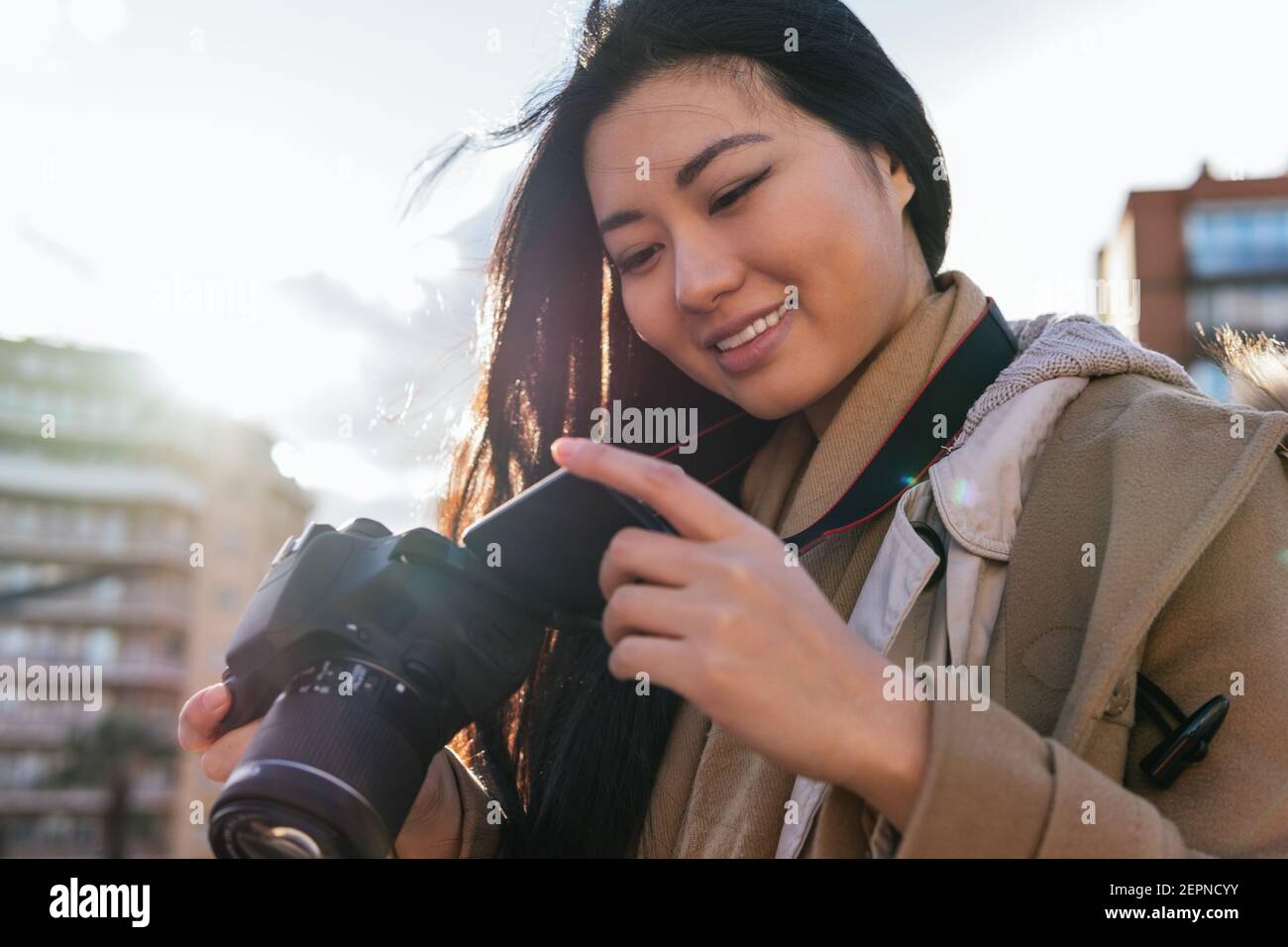 Etnico giovane felice asiatica fotografo femminile scatto foto su professionista fotocamera sulla strada della città Foto Stock