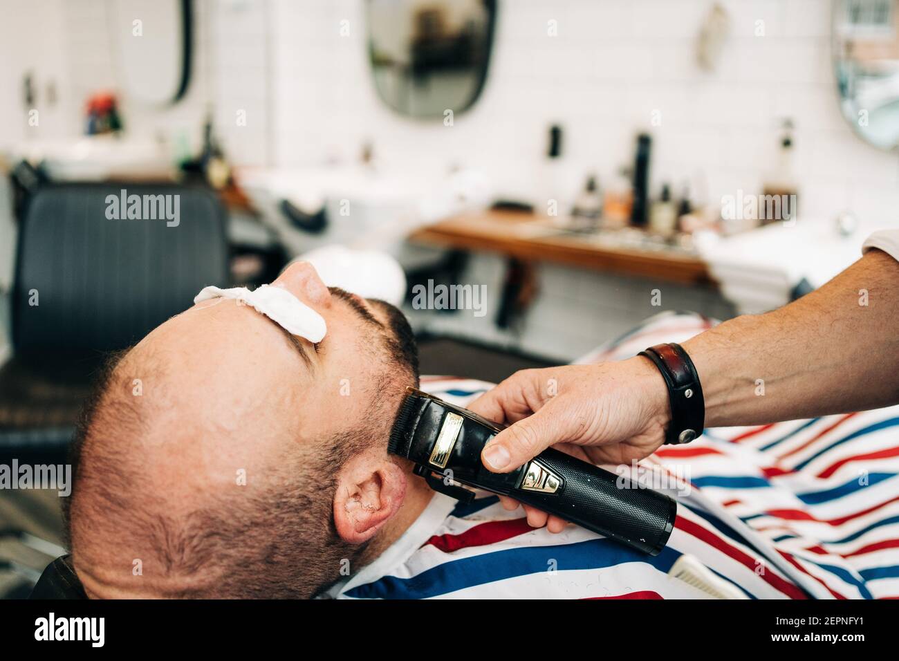 Crop anonimo master barba di taglio uomo maschile con elettrico macchina in parrucchiere Foto Stock
