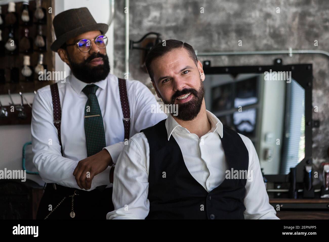 Allegro imprenditore adulto maschio con mascolino maturo maestro di bellezza etnica in abiti formali in barbiere Foto Stock
