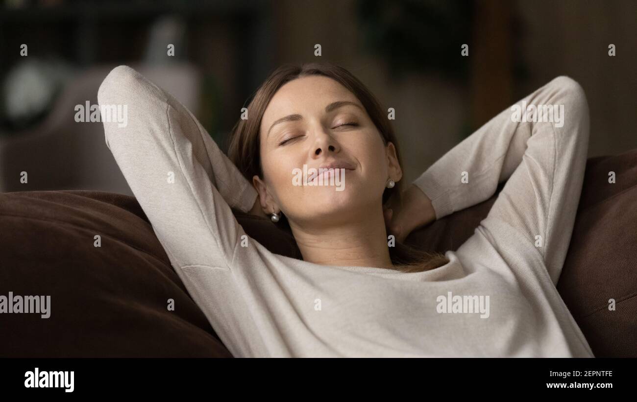 Calma giovane donna rilassarsi su divano daydreaming Foto Stock