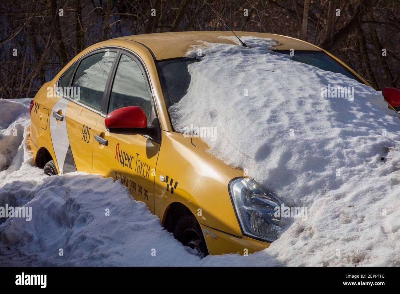Un taxi giallo con l'iscrizione 'Yandex taxi' sulla porta dell'auto si trova sotto una neve su una strada a Mosca, Russia Foto Stock
