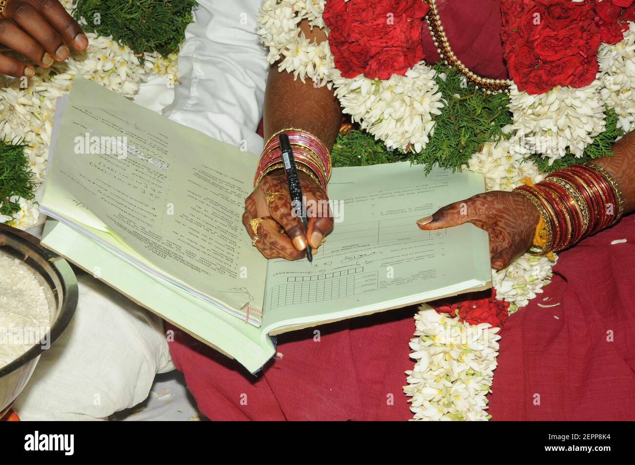 Sposo e sposo di nozze dell'India del sud che firmano la registrazione di matrimonio in abbigliamento da sposa Foto Stock