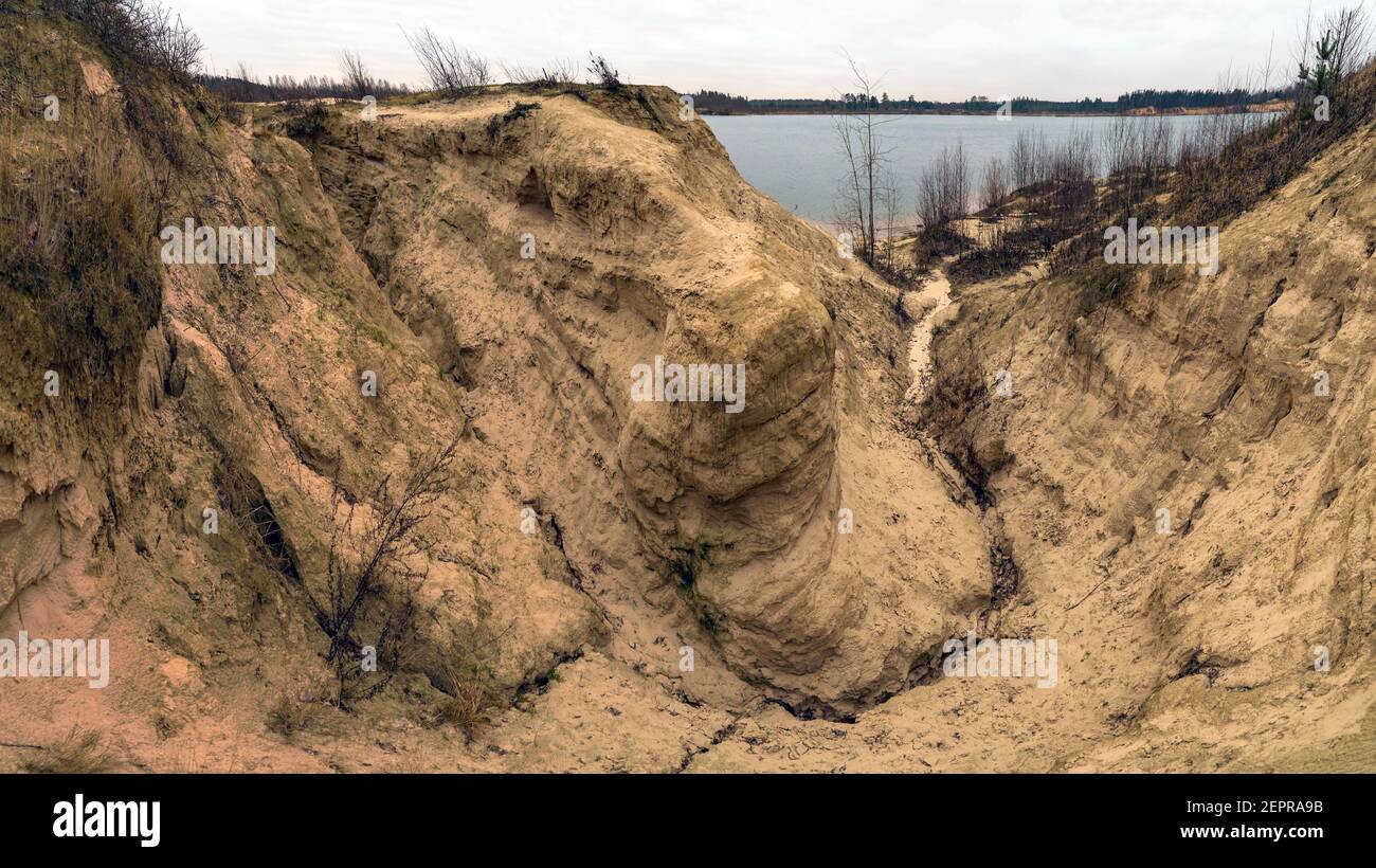 Canyon sabbioso dilavato da ruscelli sulla riva del lago nel tardo autunno. Regione di Leningrad. Cava di Pugarevsky. Foto Stock