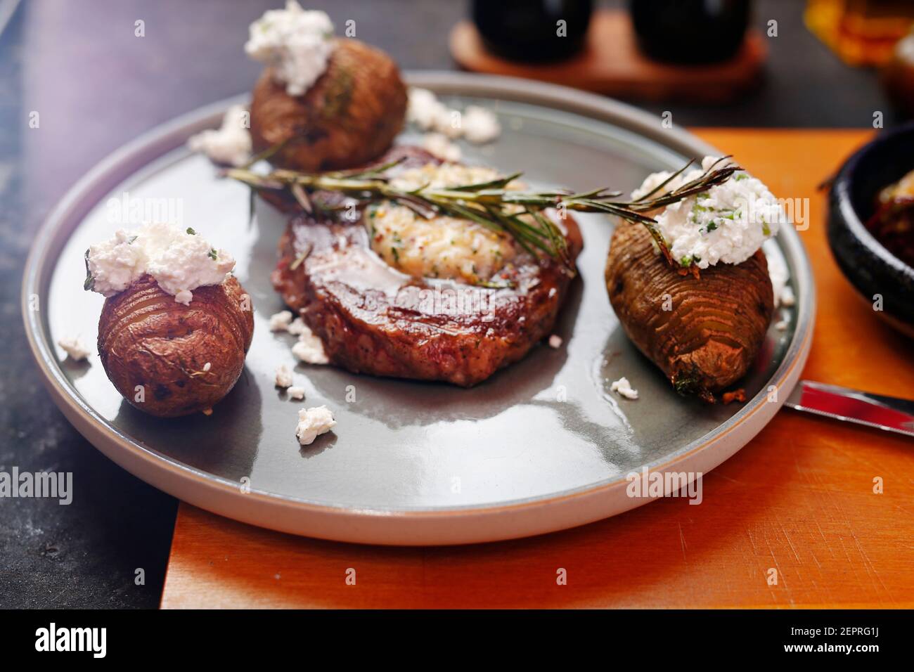 Bistecca di manzo con burro all'aglio, patate al forno con formaggio casolare. Cibo servito su un piatto, stile del cibo, servendo suggerimenti, fotografia culinaria. Foto Stock