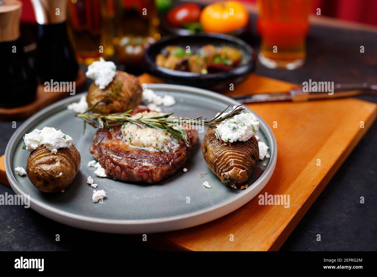 Bistecca di manzo con burro all'aglio, patate al forno con formaggio casolare. Cibo servito su un piatto, stile del cibo, servendo suggerimenti, fotografia culinaria. Foto Stock