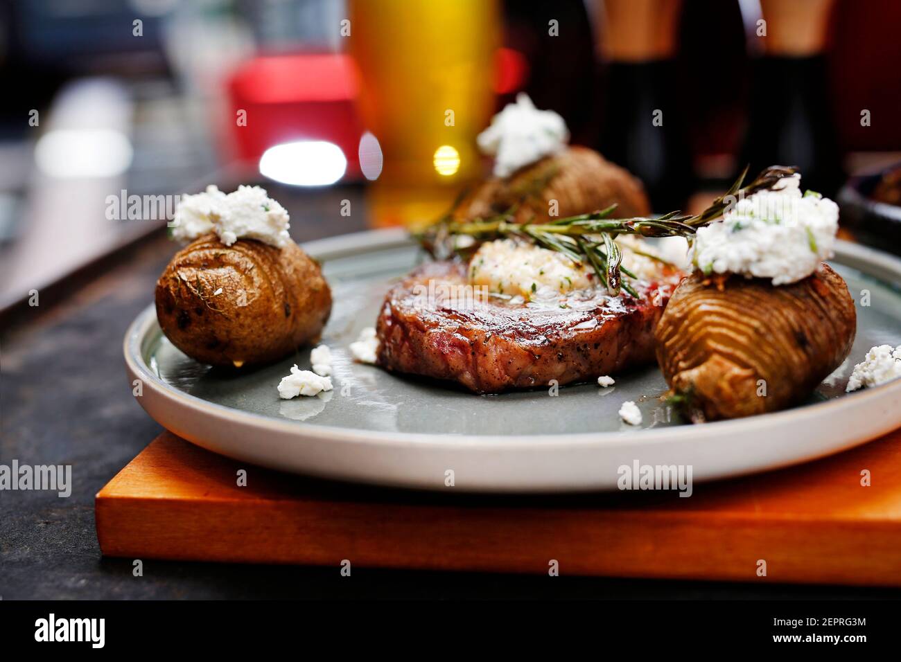 Bistecca di manzo con burro all'aglio, patate al forno con formaggio casolare. Cibo servito su un piatto, stile del cibo, servendo suggerimenti, fotografia culinaria. Foto Stock