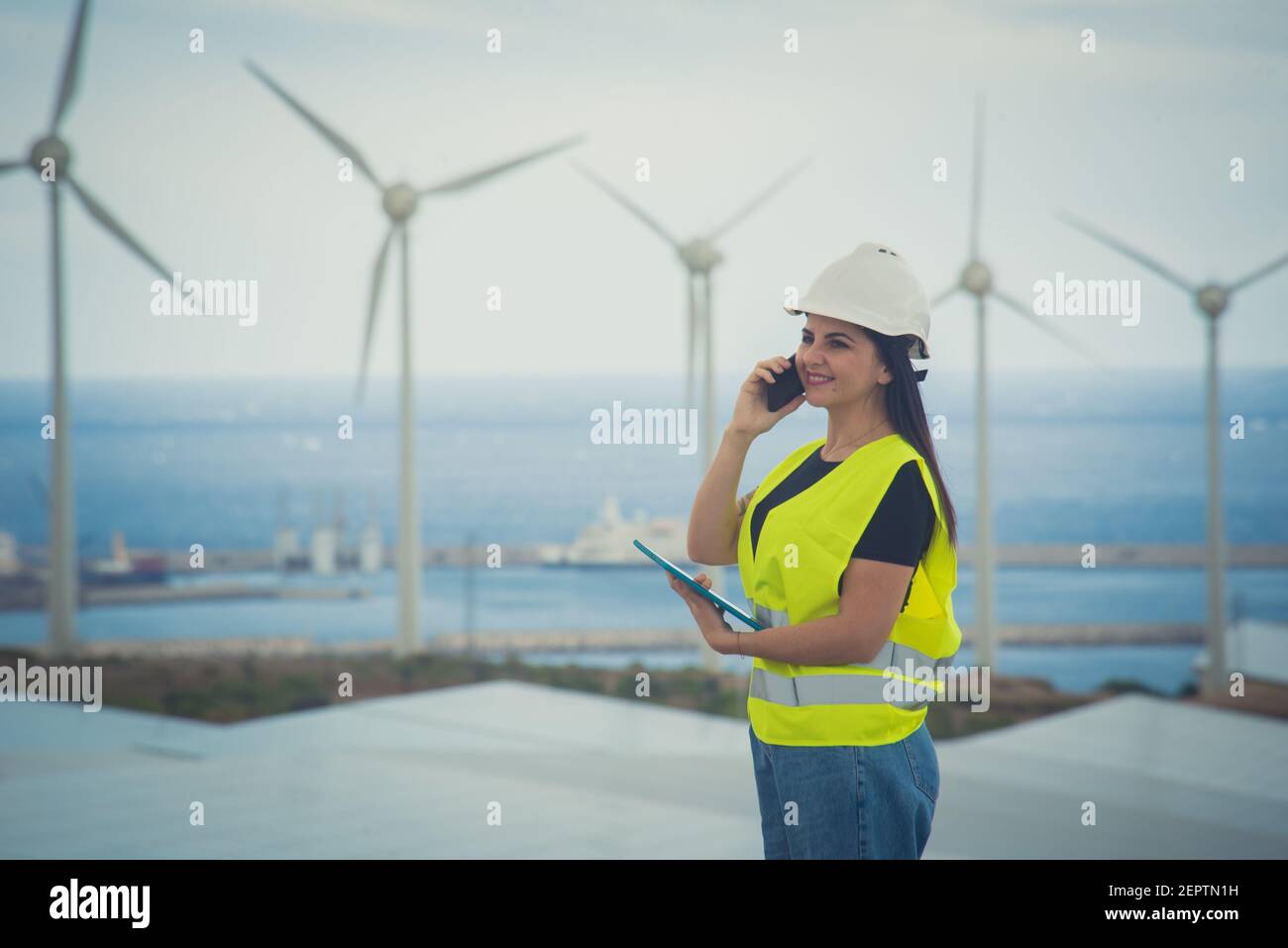 l'ingegnere femminile adulto supervisiona i pannelli solari e mulini a vento in un energia rinnovabile complesso Foto Stock