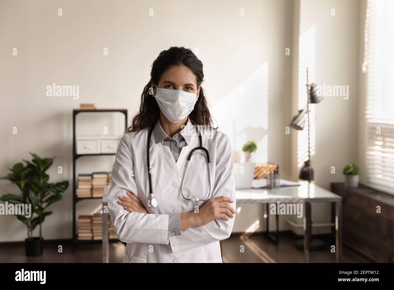 Ritratto professionale dottoressa con maschera medica in piedi in ufficio Foto Stock
