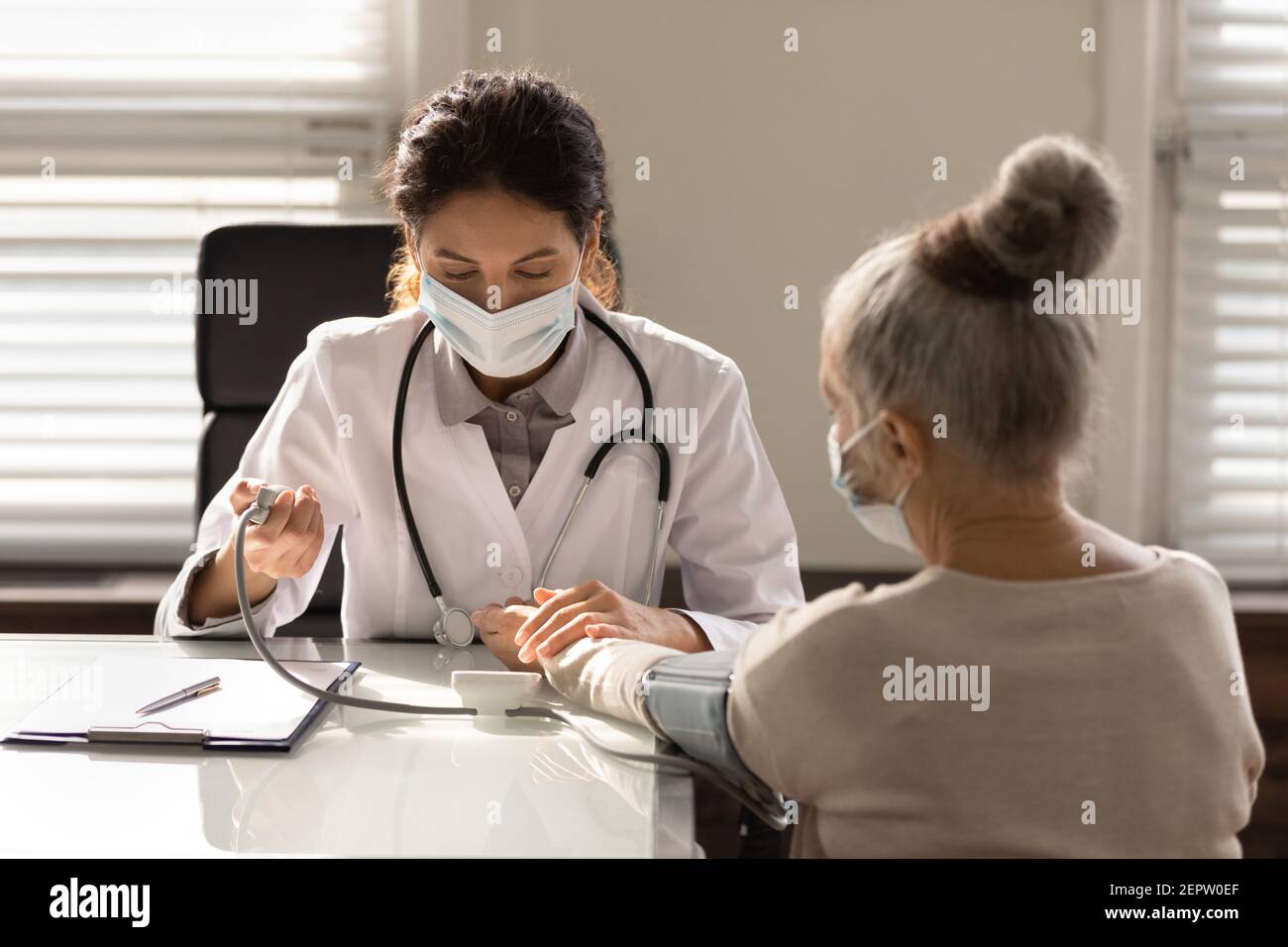 Primo piano medico indossando maschera di misurazione della pressione sanguigna della vecchia donna Foto Stock