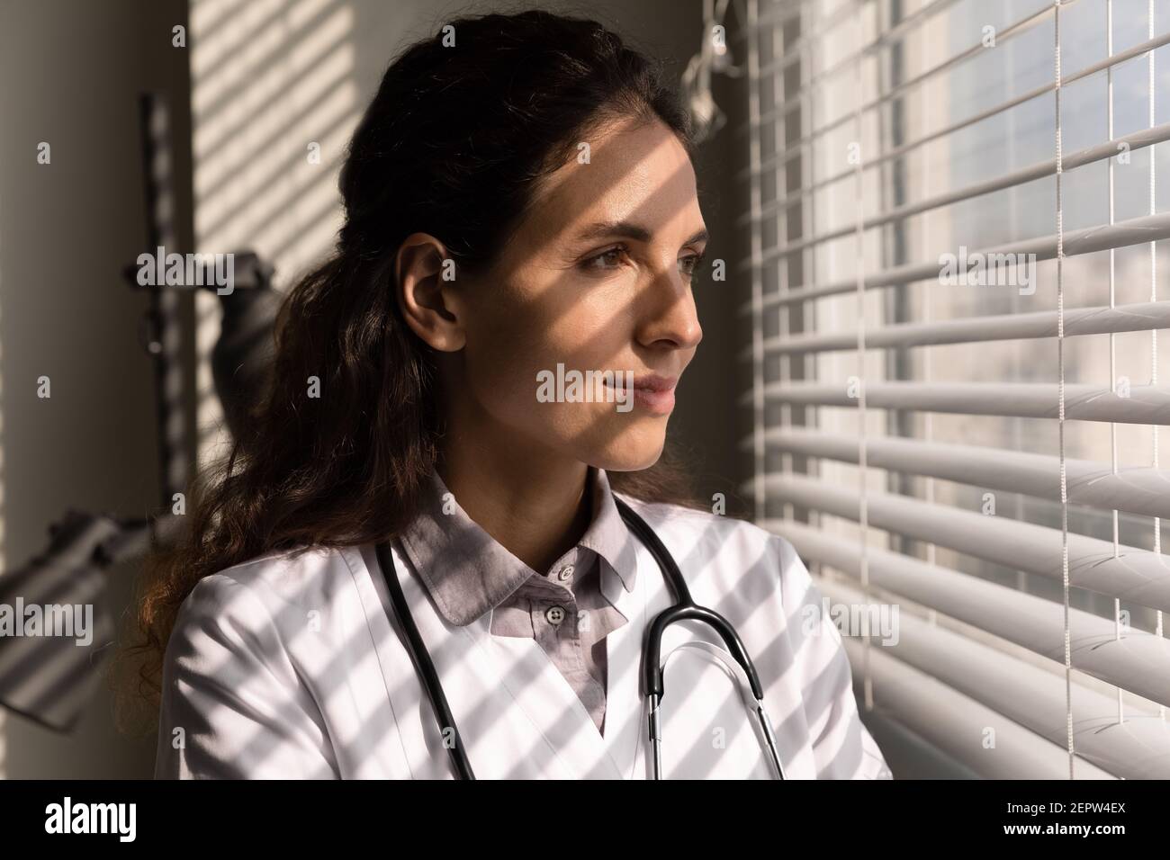 Head shot primo piano medico femminile sognando, guardando fuori finestra Foto Stock