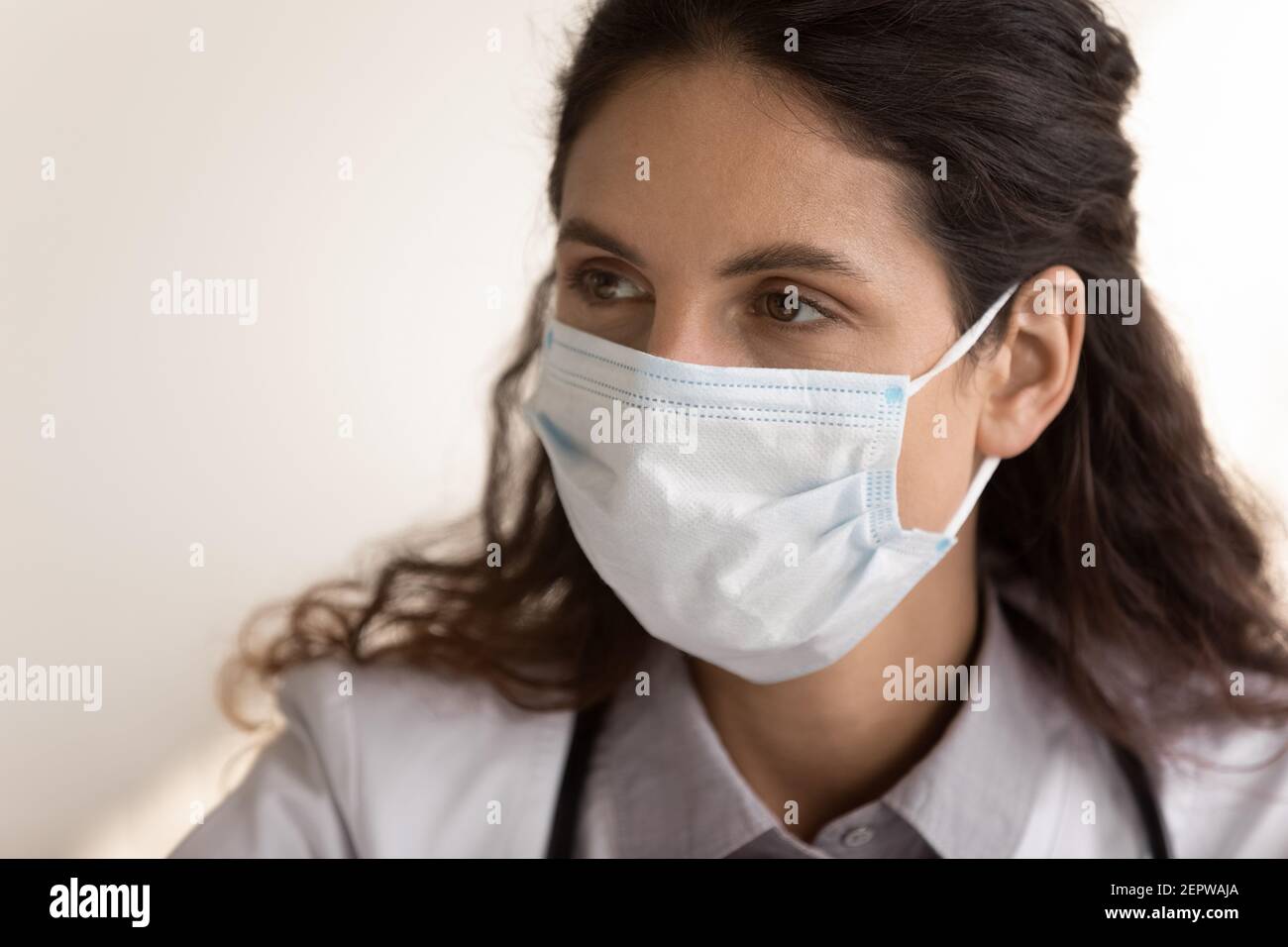 Primo piano meditato medico donna che indossa maschera medica viso Foto Stock