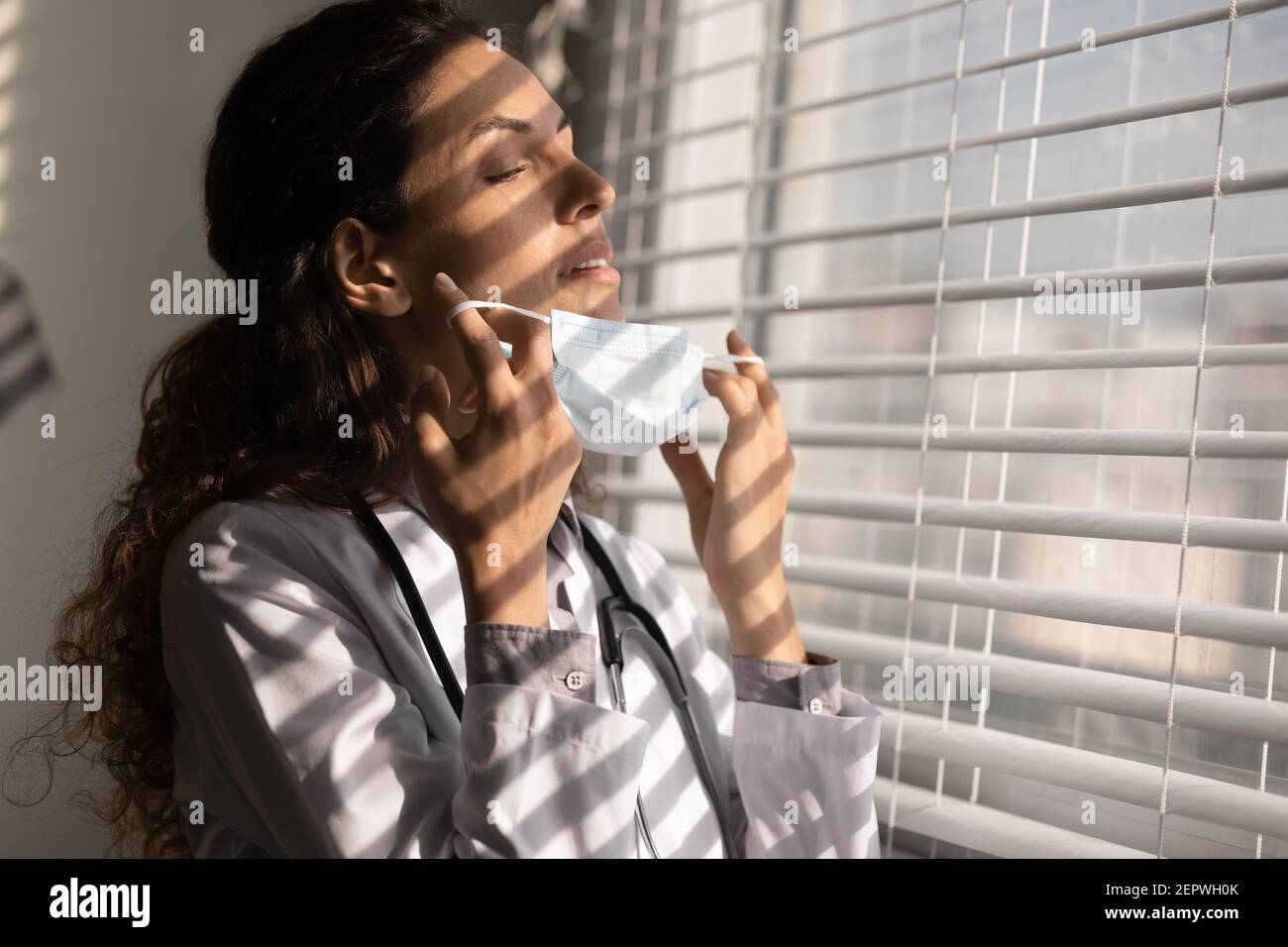 Primo piano medico donna stanco togliendo maschera medica viso Foto Stock