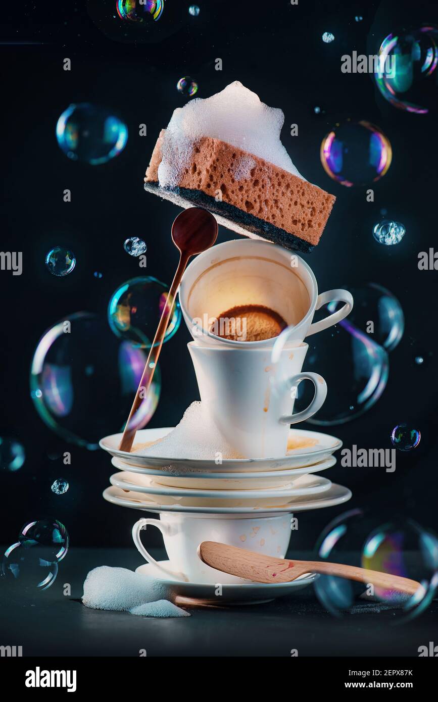 Piatti sporchi e tazze di caffè con spugne e bolle, concetto di bellezza mondana Foto Stock