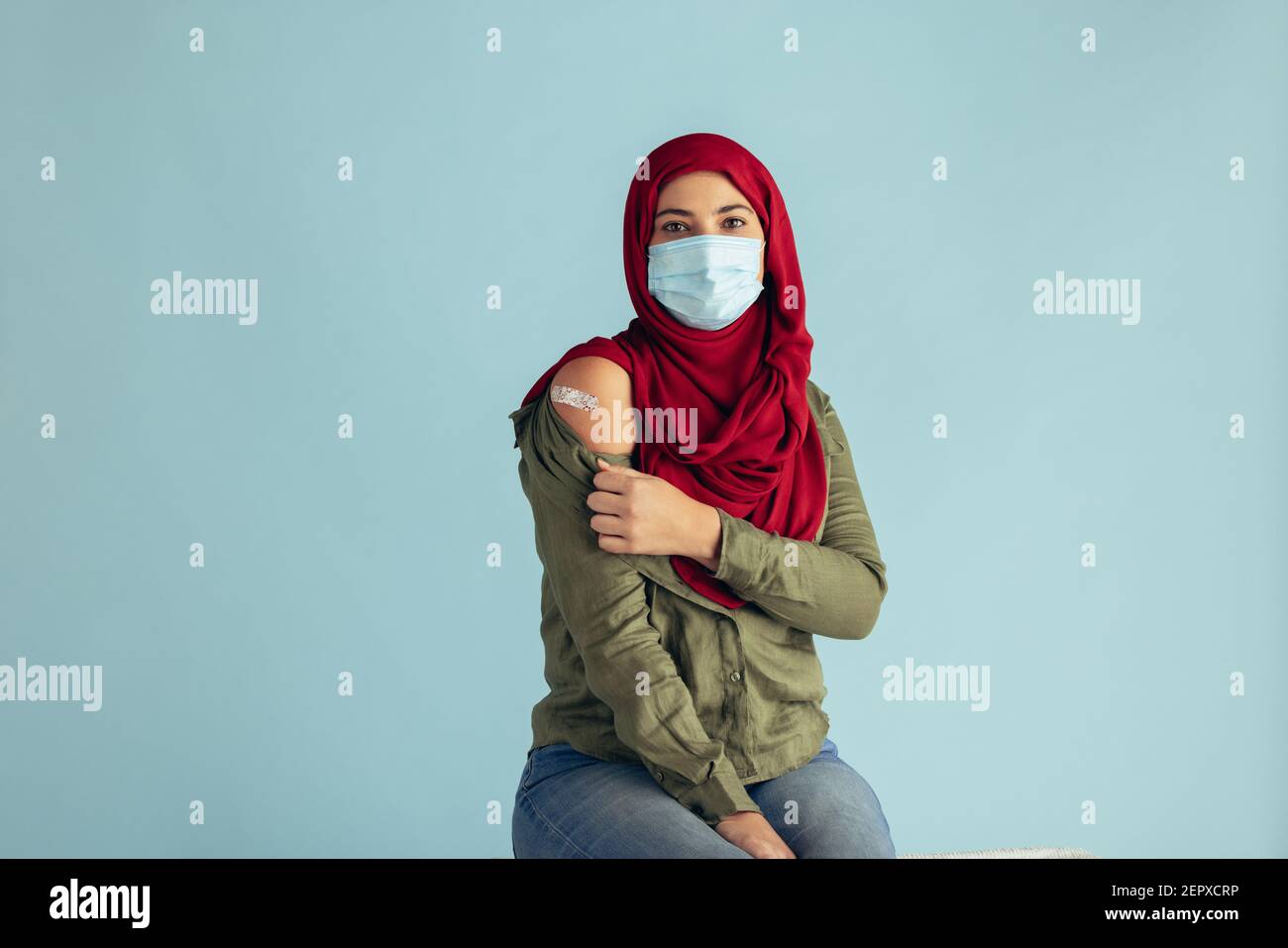 Donna musulmana che indossa una maschera protettiva che mostra il suo braccio con aiuto di banda dopo aver ricevuto la vaccinazione. Le donne in hijab hanno ricevuto il vaccino del virus corona. Foto Stock