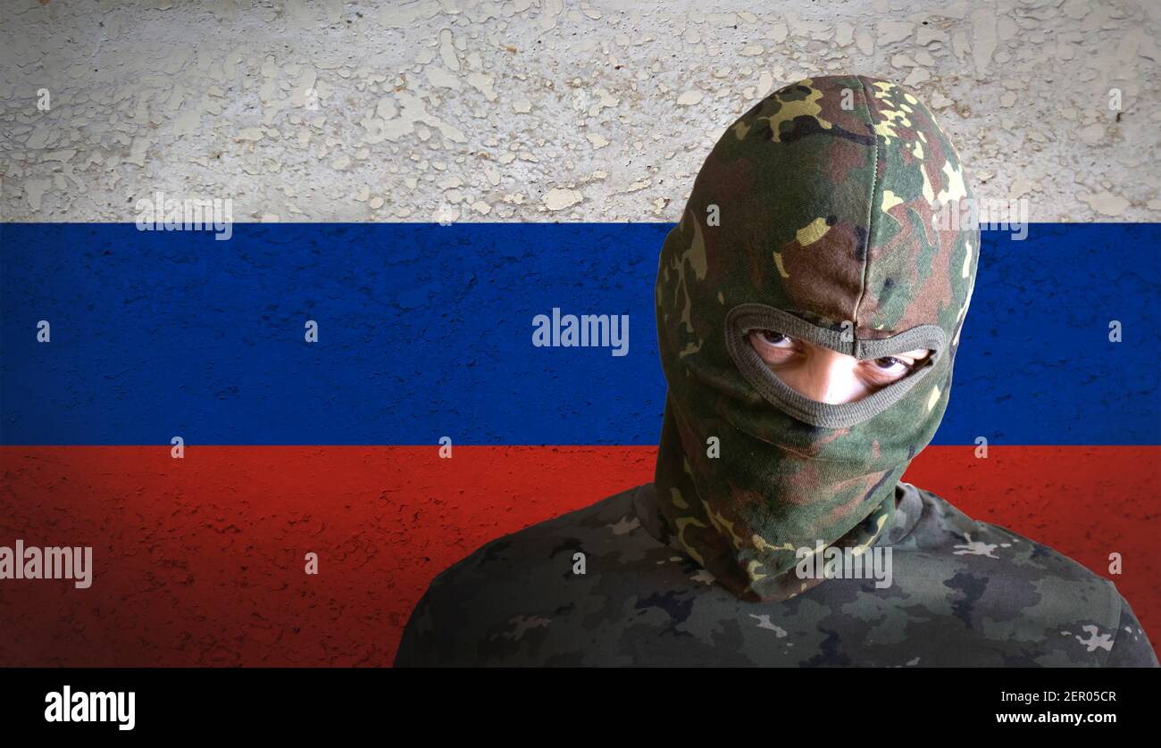 Soldato russo arrabbiato con la bandiera russa alle spalle. Militare spetsnaz uomo con camuffamento e arrabbiato aggressivo per la guerra. Foto Stock