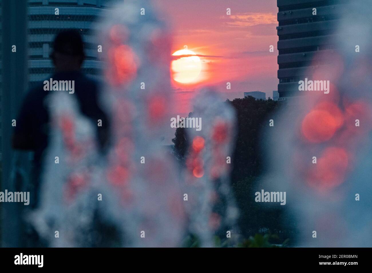 Singapore. 28 Feb 2021. La luce di un sole tramonta passa attraverso una fontana d'acqua nel Singapore Sports Hub il 28 febbraio 2021. Credit: Allora Chih Wey/Xinhua/Alamy Live News Foto Stock