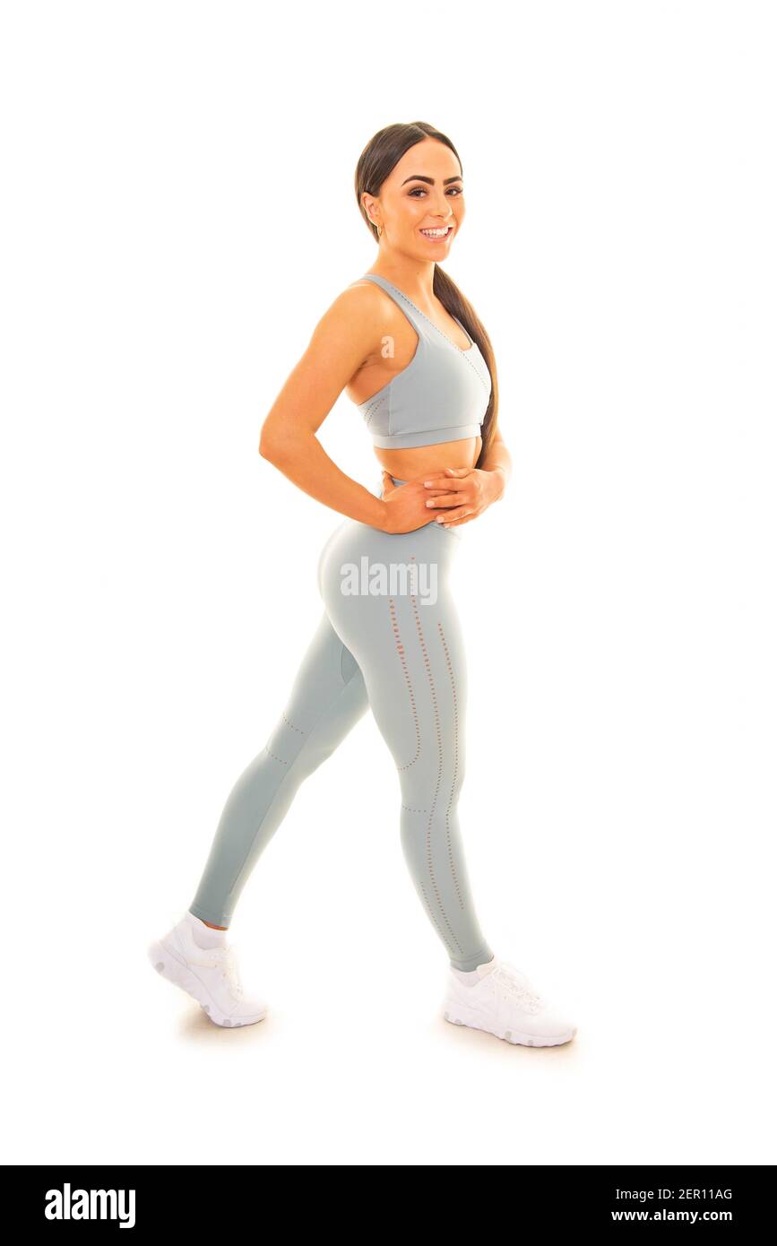 Ritratto verticale di una giovane donna che posa in un abbigliamento da fitness, isolato su uno sfondo bianco. Foto Stock