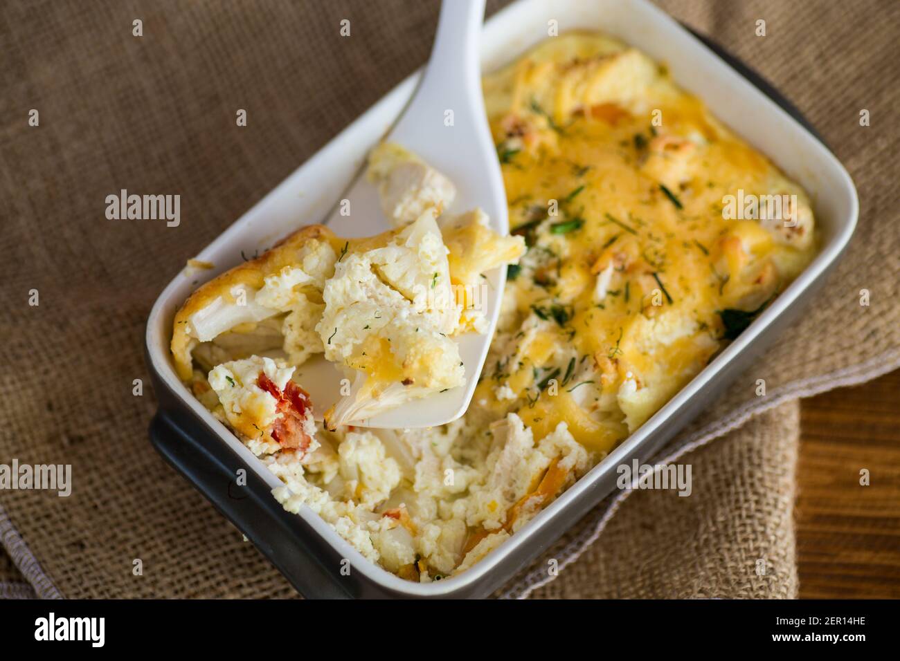 cavolfiore al forno con filetto di pollo e verdure condite con formaggio in uno stampo di ceramica Foto Stock