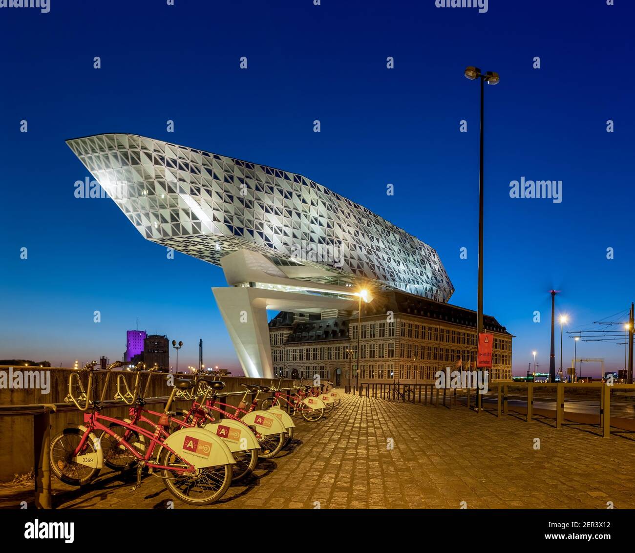 L'edificio della Port House di Anversa di notte con una linea Di biciclette della città di Anversa (Antwerp Velo) Foto Stock