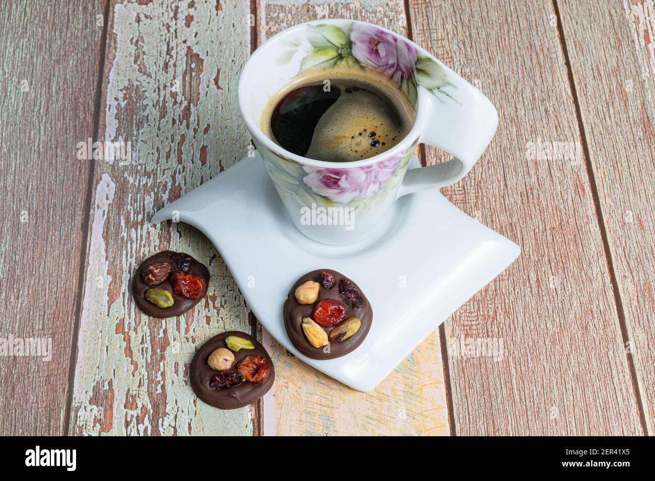 Tre piccoli biscotti al cioccolato con noci, accanto a una tazza di caffè. Foto Stock