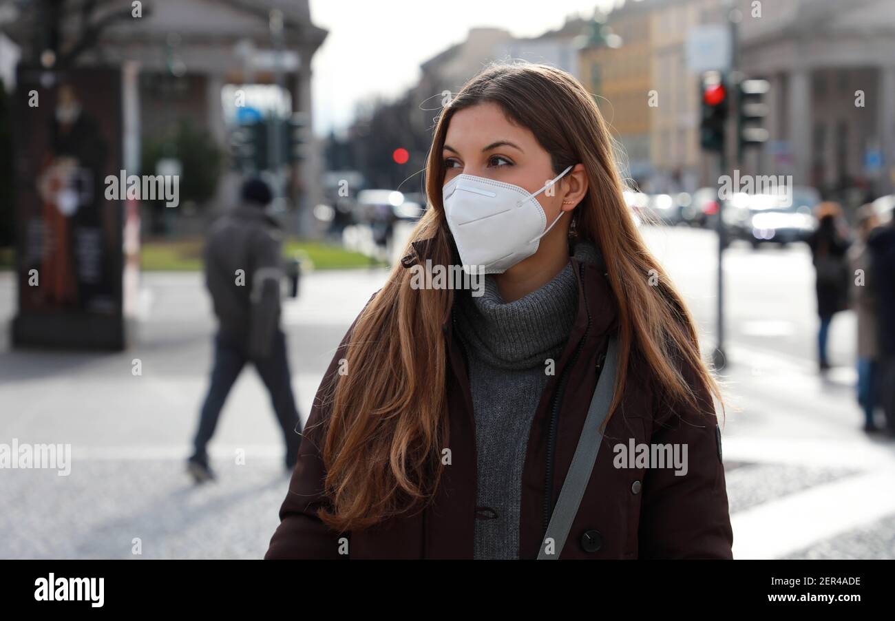 Senso di smarrimento. Giovane donna in abiti invernali che cammina per strada indossando una maschera protettiva FFP2 KN95. Ragazza con maschera viso che si sente da sola durante una p Foto Stock