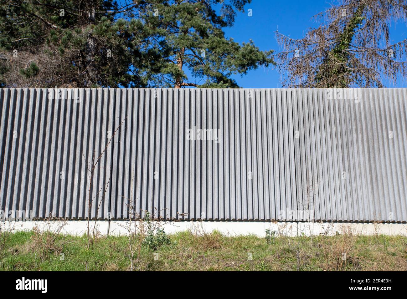 muro di protezione dal rumore, alberi e cielo in piano sullo sfondo Foto Stock