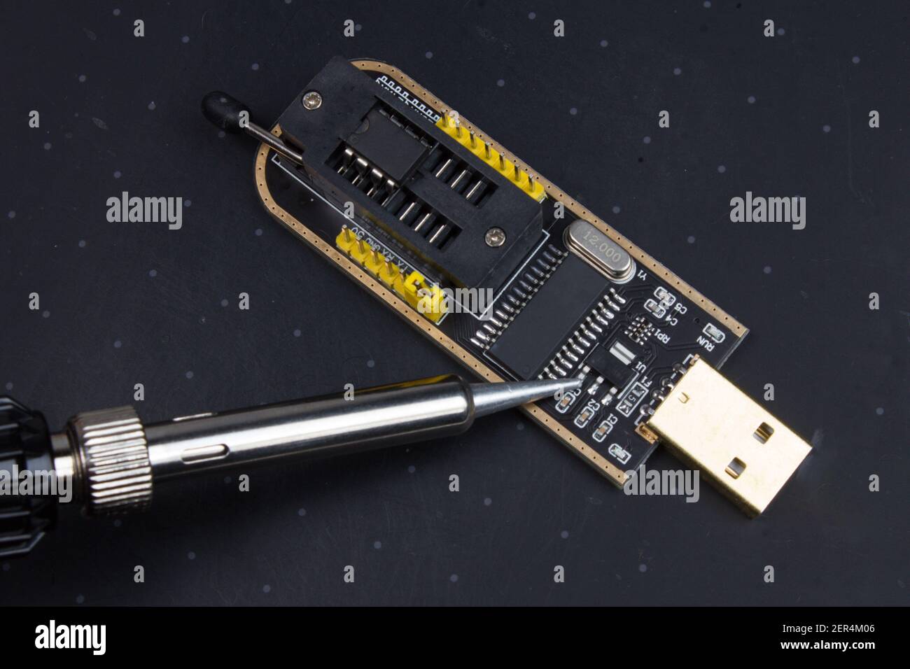 Programmatore con memoria microchip inserita e saldatore. Riparazione elettronica radio Foto Stock