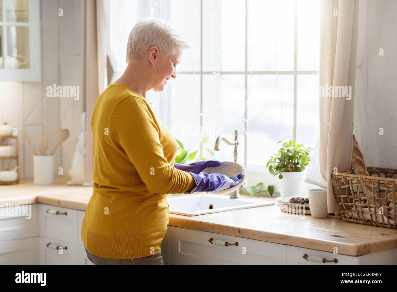 Signora senior lavare piatti in cucina, utilizzando guanti di gomma Foto  stock - Alamy