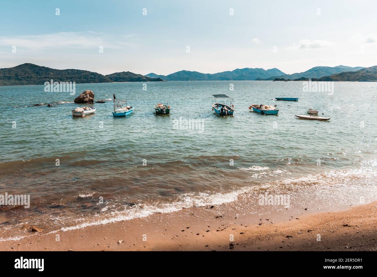 Foto di viaggio dei Caraibi impostazione di Peng Chau Island Sandy Beach con acque turchesi blu e barche da pesca, Hong Kong Foto Stock