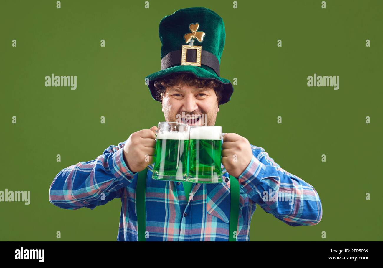 Divertente uomo eccitato che celebra il giorno di San Patrizio e bere verde birra da due tazze Foto Stock