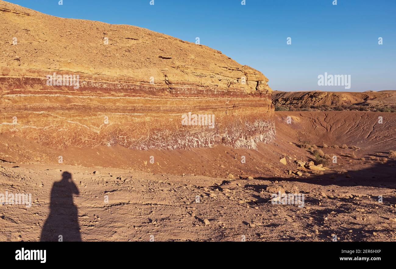 vista dell'ora d'oro di una delle vecchie cave di il cratere di makhtesh ramon in israele, con l'ombra di il fotografo Foto Stock