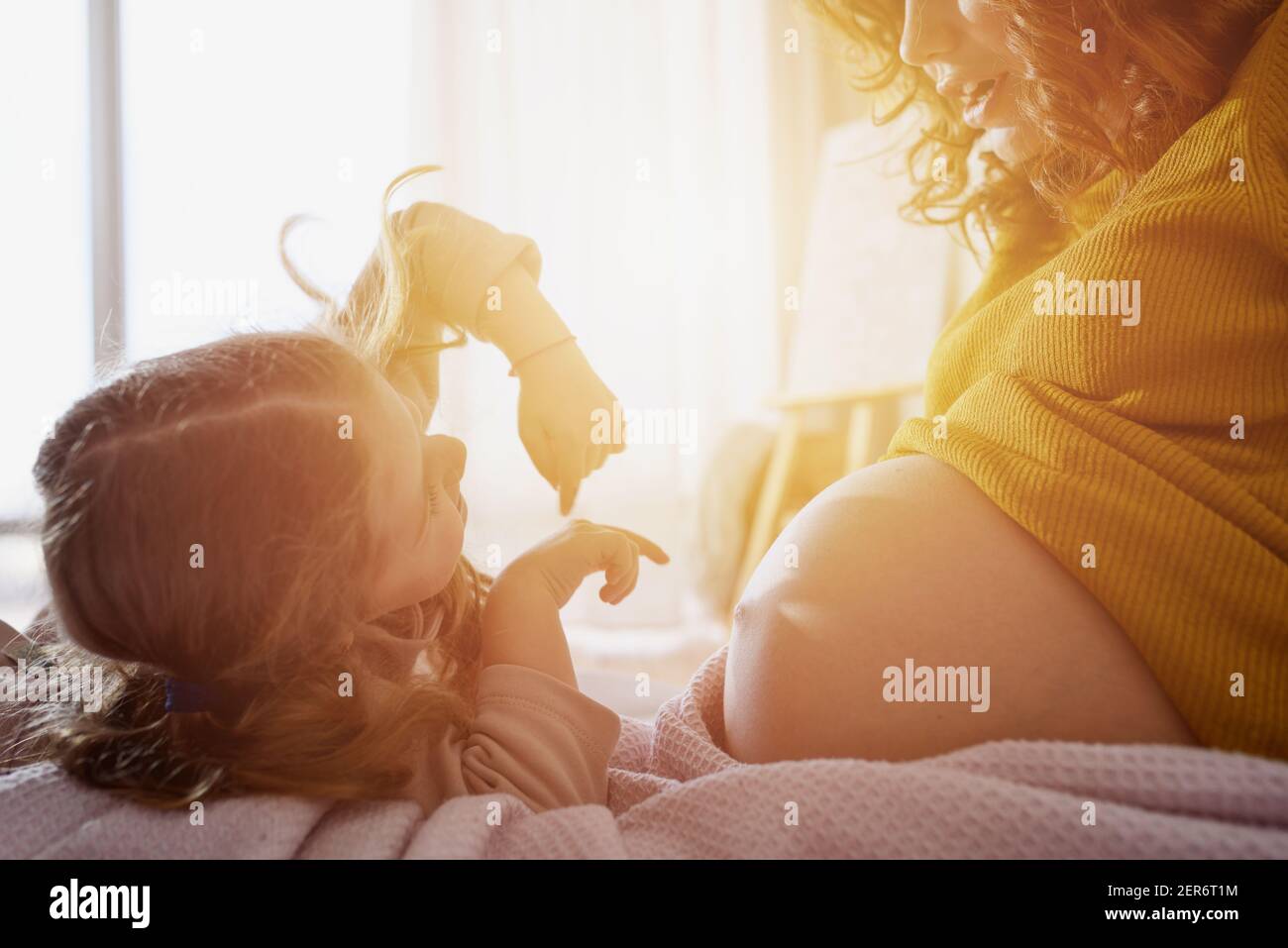 Mamma incinta gioca con sua figlia. Concetto di famiglia, gioia e gravidanza Foto Stock