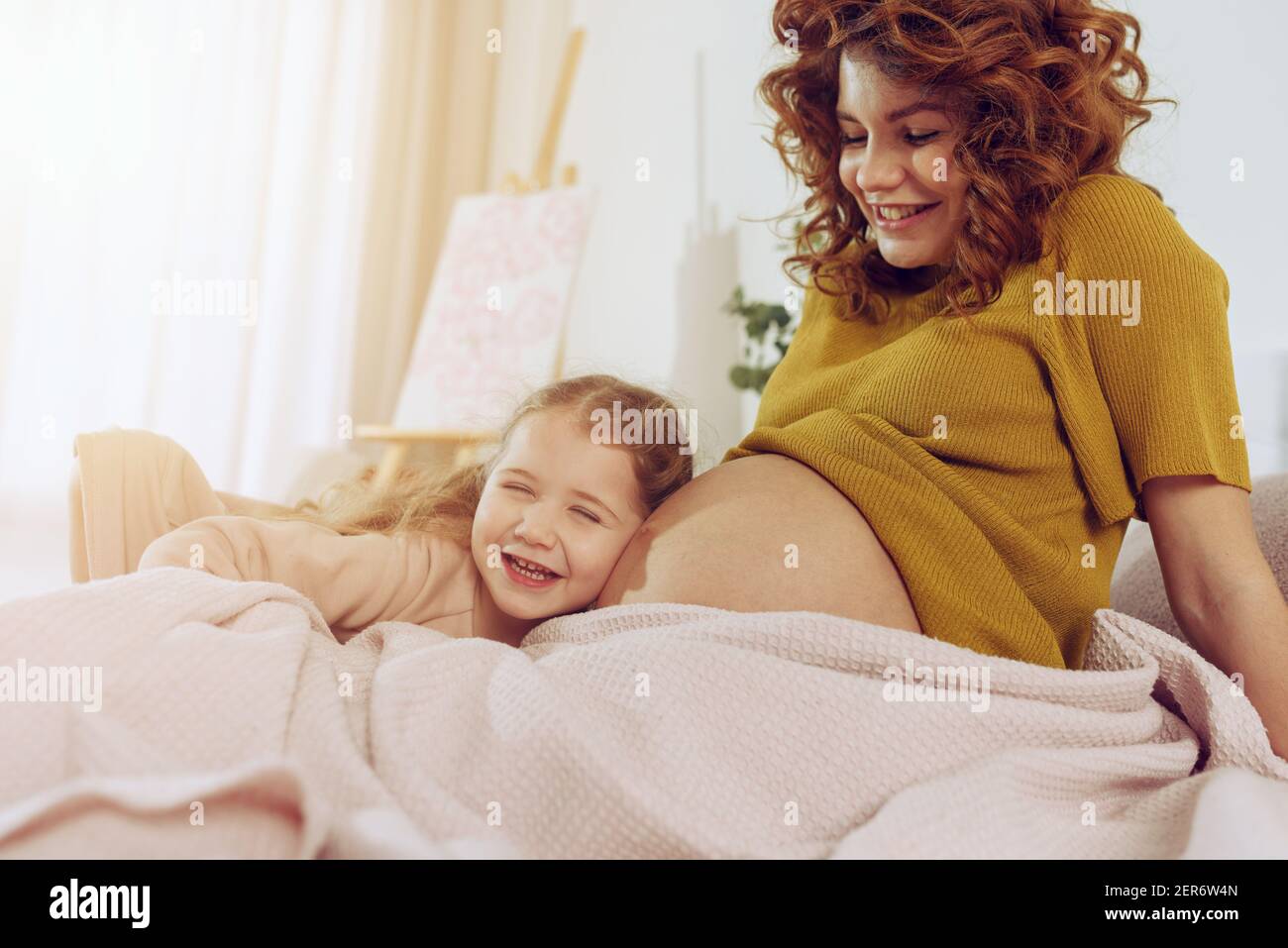 Mamma incinta gioca con sua figlia. Concetto di famiglia, gioia e gravidanza Foto Stock