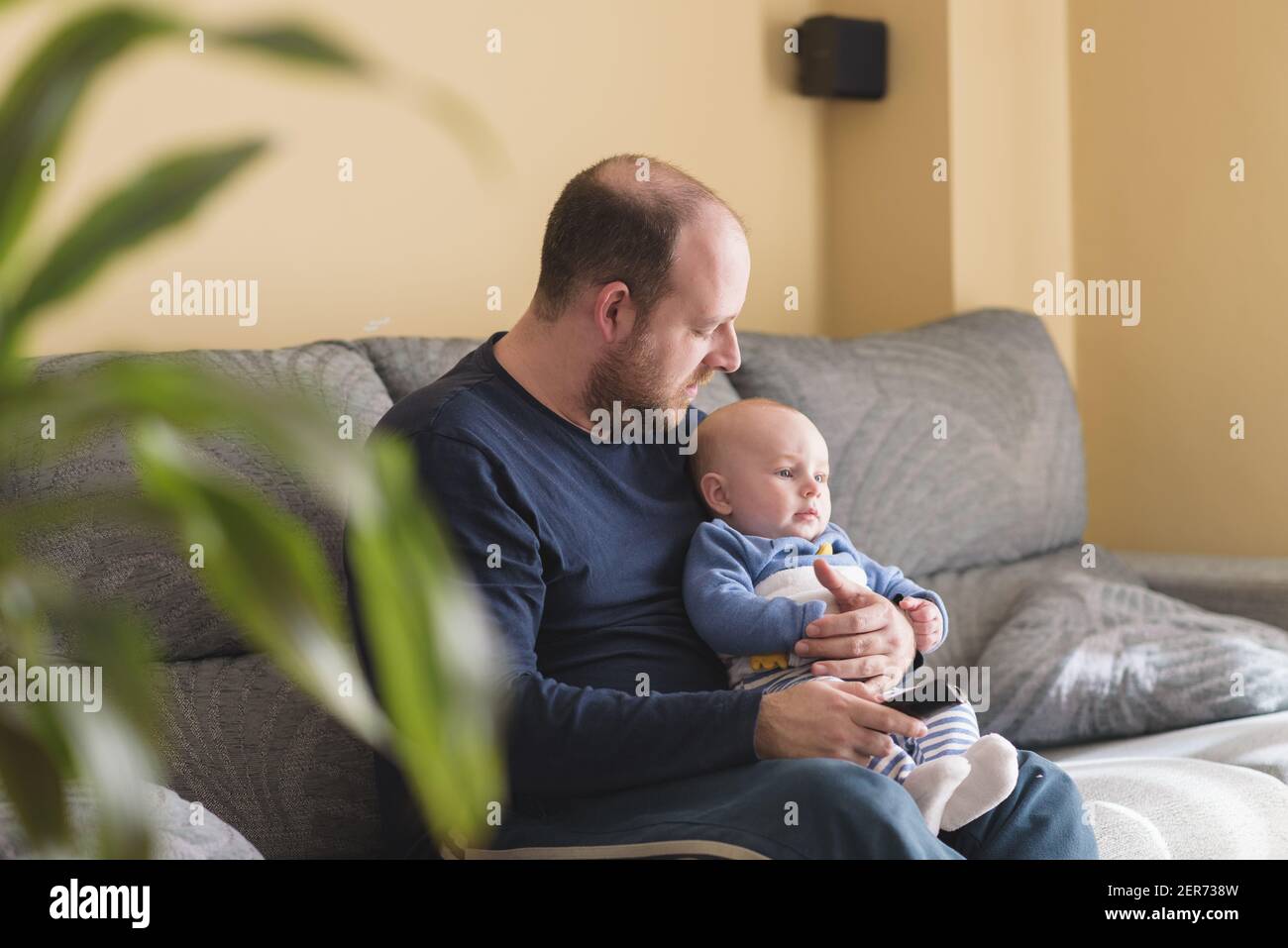 Vita domestica del papà in congedo di paternità. Padre e figlio guardano il calcio in TV a casa. Essere a casa in tempi di pandemia Foto Stock