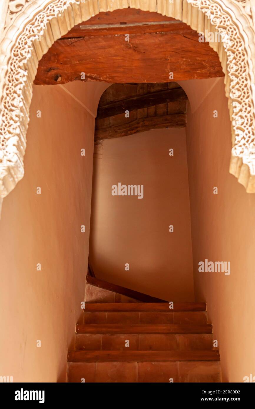 Una vecchia scala in pietra con un ingresso ad arco e uno stretto passaggio in pietra che sale in un edificio storico. Il cancello ad arco ha motivi ornamentali e textu Foto Stock