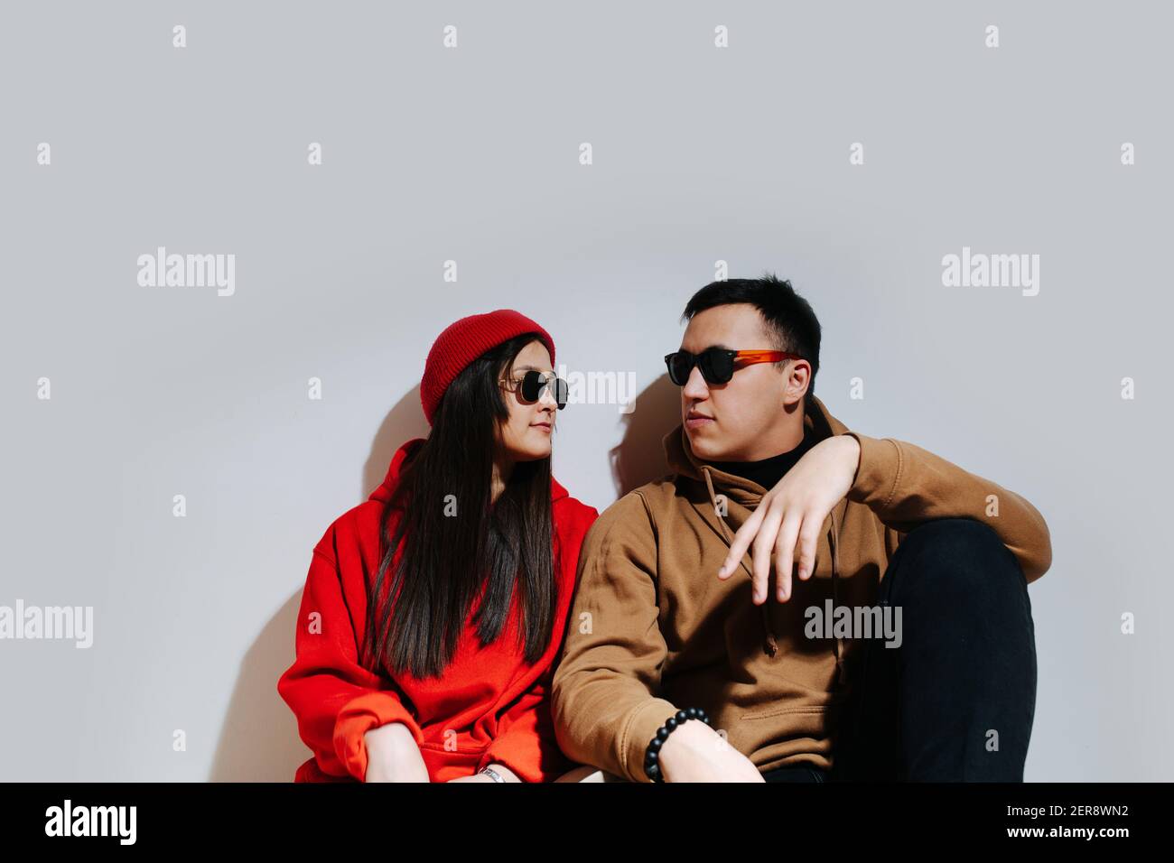 Uomo e donna seduti a spalla al sole occhiali protettivi Foto Stock