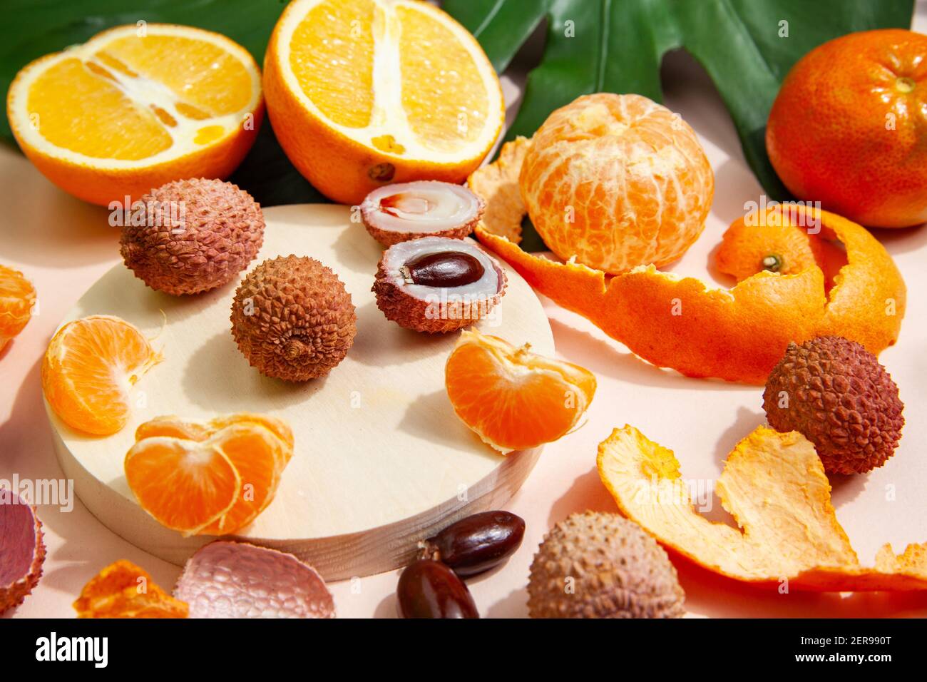 Gustosi litchi e arance arrangiate su tavola rosa Foto Stock