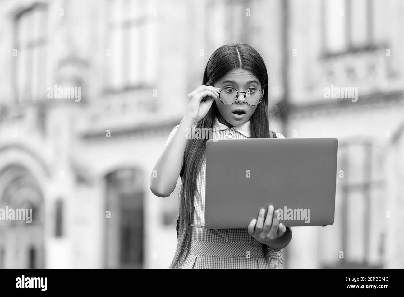 allievo sorpreso di stile ragazza che studia i compiti durante la sua lezione in linea mentre distanza sociale durante la quarantena, concetto di formazione in linea. Foto Stock