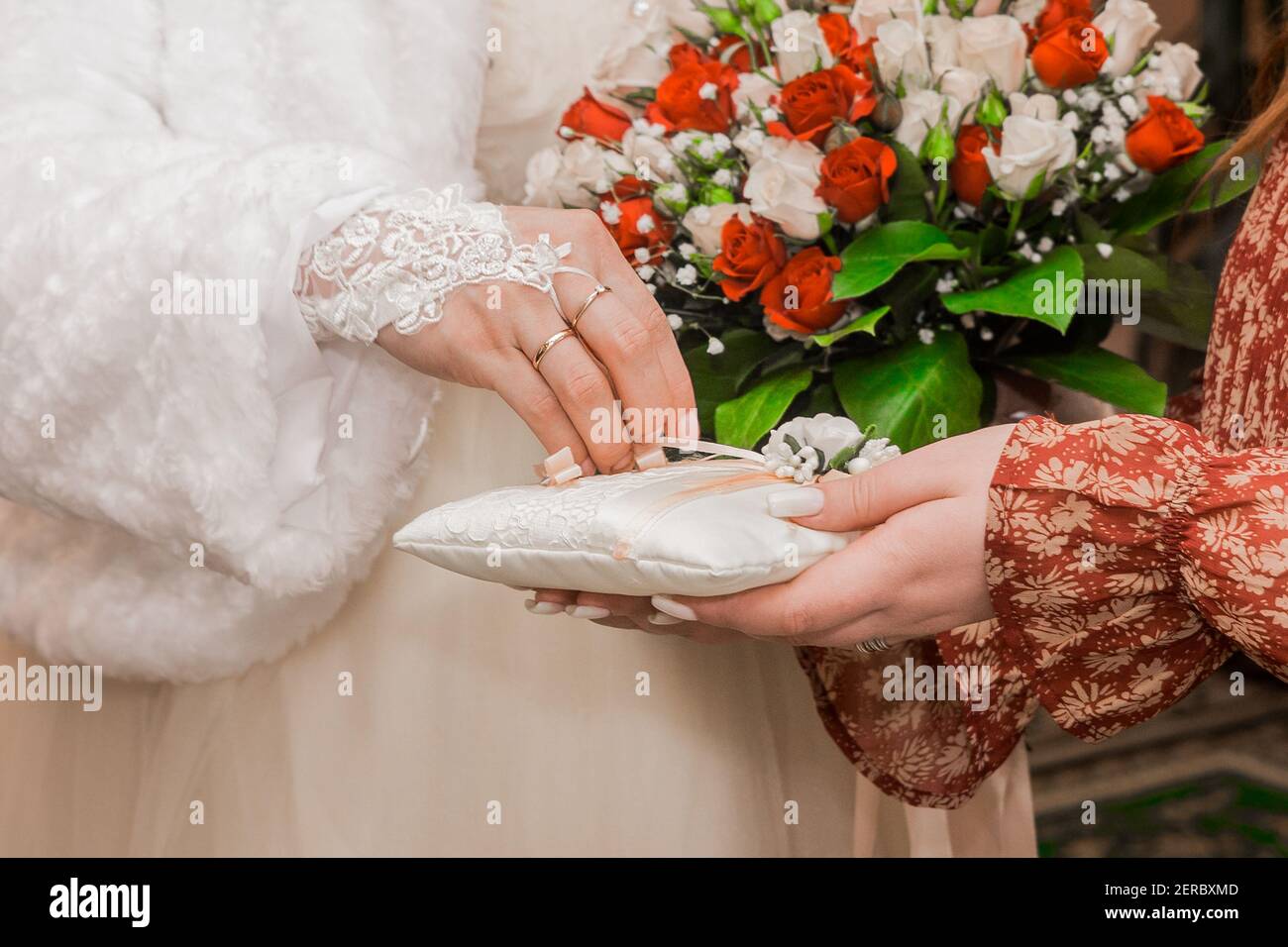La mano della sposa nel guanto di nozze prende l'anello di matrimonio. Primo piano degli anelli di nozze. Foto Stock