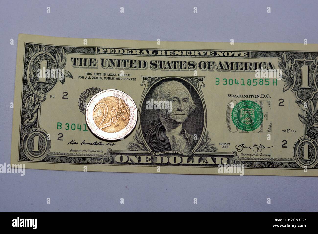 Una banconota in dollari americani e una moneta da 2 euro, moneta americana  contro moneta europea, concentrazione selettiva Foto stock - Alamy