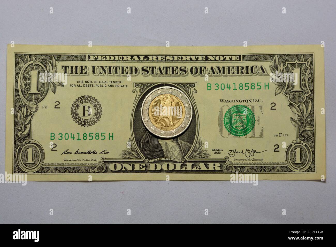 Una banconota in dollari americani e una moneta da 2 euro, moneta americana contro moneta europea, concentrazione selettiva Foto Stock