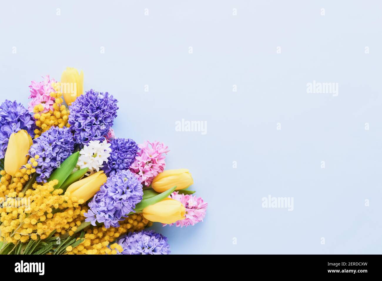 Bouquet di fiori primaverili su sfondo azzurro. Festa della mamma, giorno di San Valentino, concetto di celebrazione del compleanno. Vista dall'alto, spazio di copia per il testo. Foto Stock