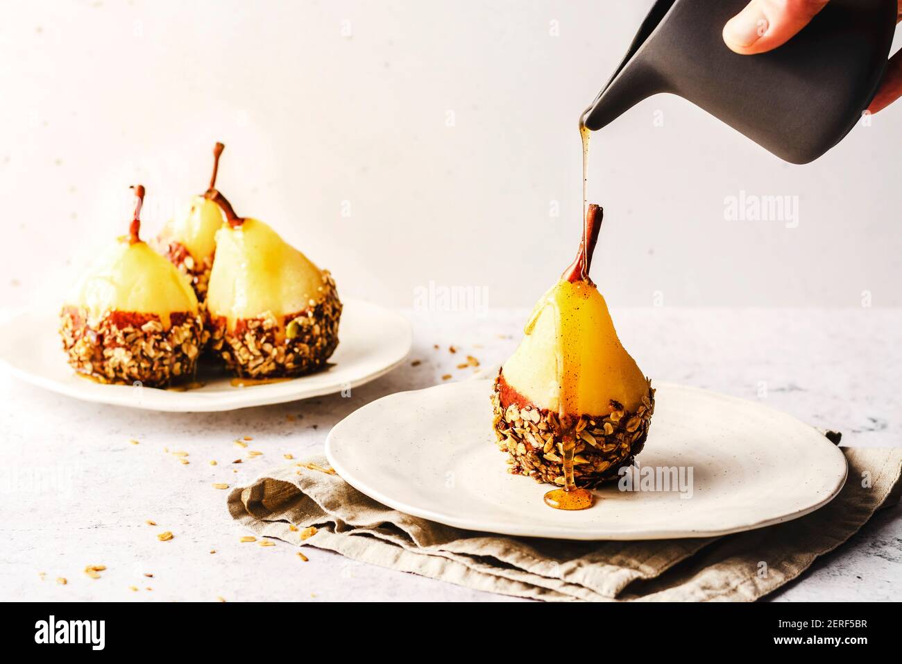 Pero in camicia con cioccolato e muesli fatti in casa, su un piatto di withe con sciroppo sulla parte superiore. Foto Stock