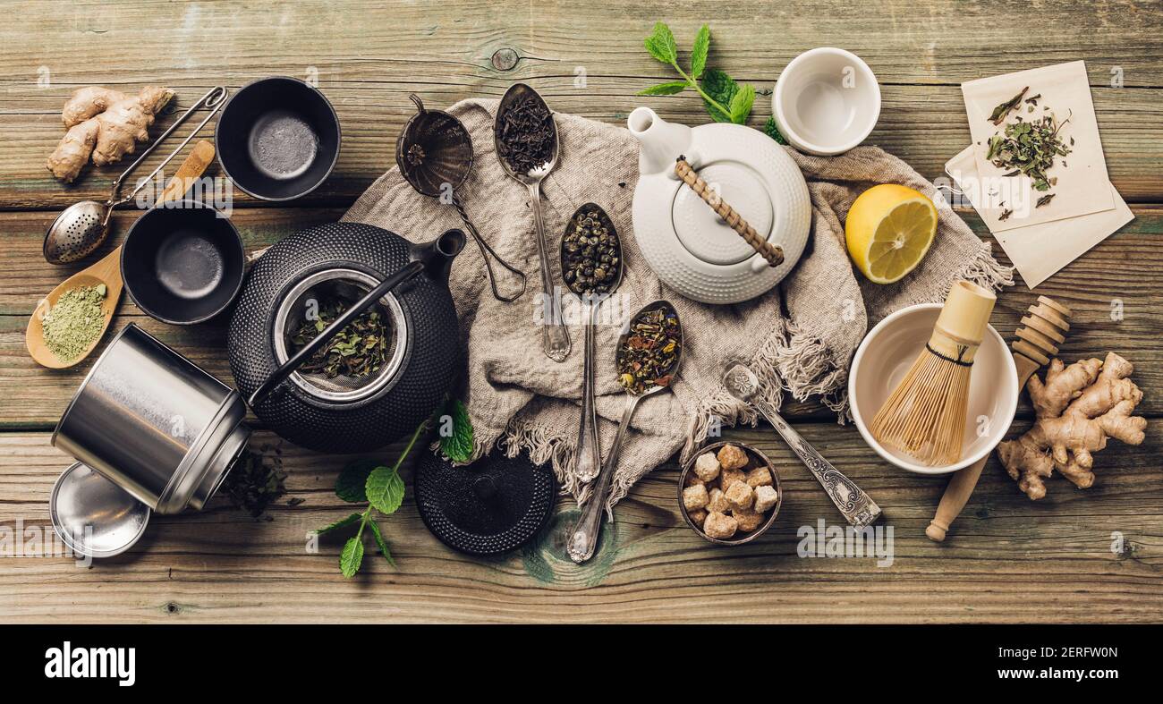 Vari tè e teiera composizione, erbe essiccate, tè verde, nero e tè matcha su fondo tavola di legno, piatto Foto Stock